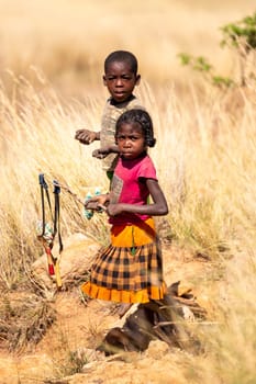 Andringitra Mountains, Madagascar - November 15th 2022: Local young girl and boy selling souvenirs standing in mountainous landscape. Andringitra, Madagascar