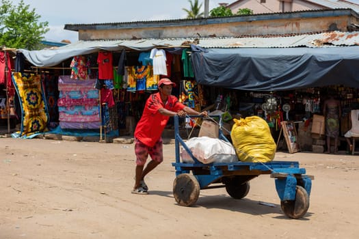 Miandrivazo, Madagascar - November 2nd 2022: A man engaged in transporting bags pushes a primitive cart on the streets of Miandrivazo.