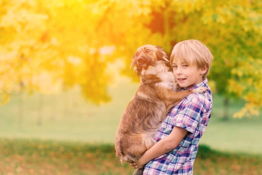 Boy hugging a dog and playing with in the fall, city park