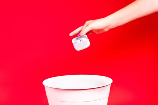 Shot of young woman hand throwing her outwear dress in the trash isolated on red background