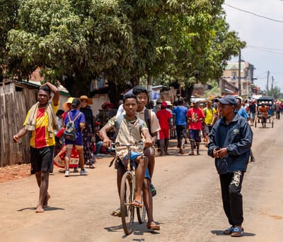 MANDOTO, MADAGASCAR - NOVEMBER 9 2022: The Malagasy students with uniforms on bike are a symbol of hope for the future of Madagascar. They are bright, ambitious, and determined to change the world.