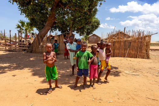 Port Bac Belo Sur Tsiribihina, Madagascar - November 4th 2022: Curious group of children looking at a tourist near the river Mania. The children live in a rural village along the riverbank.