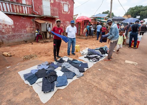 Mandoto, Madagascar - November 9th, 2022: A bustling street market in Mandoto city with vendors selling various types of clothes with vibrant colors.
