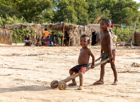 Ferry port Bekopaka, Madagascar - NOVEMBER 4 2022: Boys have fun with a simple toy on wheels at the ferry port in Bekopaka.