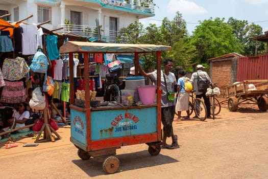 Mandoto, Madagascar - November 9th, 2022: Street in Mandoto city, with vendors and ordinary people shopping and socializing. Man sell ice cram.