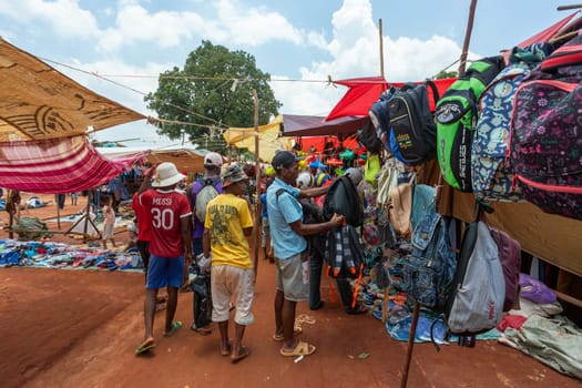 Mandoto, Madagascar - November 9th, 2022: A bustling street market in Mandoto city with vendors selling various types of clothes with vibrant colors.