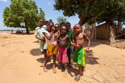 Port Bac Belo Sur Tsiribihina, Madagascar - November 4th 2022: Curious group of children looking at a tourist near the river Mania. The children live in a rural village along the riverbank.