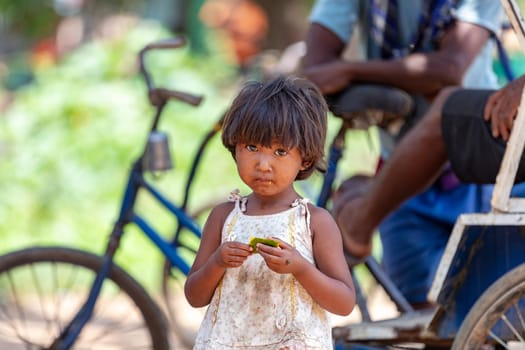 MIANDRIVAZO, MADAGASCAR - NOVEMBER 2, 2022: A young girl walks along a busy street in the city, surrounded by people and bicycles.