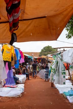 Mandoto, Madagascar - November 9th, 2022: A bustling street market in Mandoto city with vendors selling various types of clothes with vibrant colors.