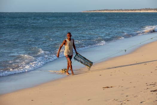 Anakao, Madagascar - November 21, 2022: A beach scene with a local fisherman and a cage for capturing crustaceans.