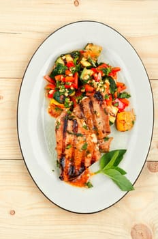 Grilled tuna steak with baked vegetables on rustic wooden table