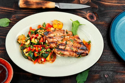 Grilled tuna steak with baked vegetables on rustic wooden table