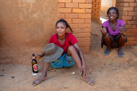 Vohitsaoka, Madagascar - November 17, 2022: Local woman drinking beer on the street at noon.