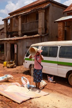 Mandoto, Madagascar - November 9th, 2022: Street market in Mandoto city, with vendors and ordinary people shopping and socializing. Woman sell rice. Local lifestyle and economy of Madagascar.