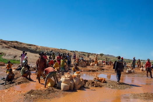 Ihosy, Ilakaka, Madagascar - November 20, 2022: Local people mine for gems and pan for gold in a river. The town is a major center of sapphire production and trade.
