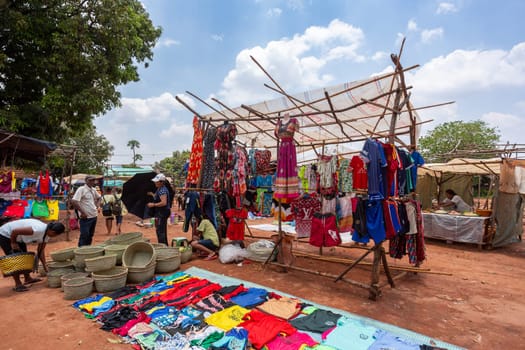 Mandoto, Madagascar - November 9th, 2022: A bustling street market in Mandoto city with vendors selling various types of clothes with vibrant colors.