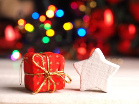 Red gift box with a white star shape and Christmas lights in the background