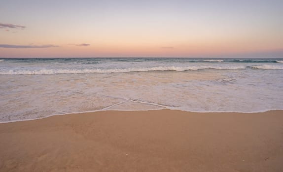 The surf and colorful sky at dusk along Kawana beach on the Sunshine Coast, Queensland, just before the Blue Moon rises above the horizon along the east coast of Australia 2023