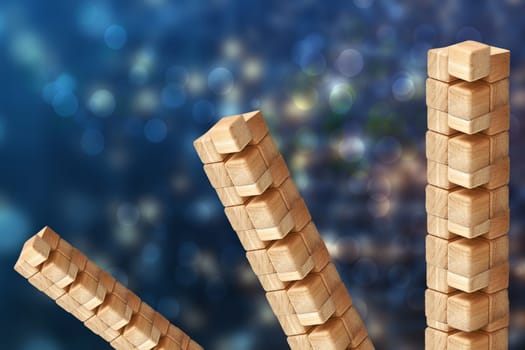 Towers from wooden blocks over abstract blurred blue technology or business  background with bright rays. Copy space. Wood blocks game.