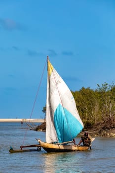 Morondava, Madagascar - November 3rd 2022: A fisherman sails back from the sea to the river on a sailboat in Morondava