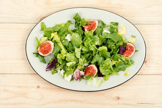 Appetizer homemade salad with figs, herbs and cheese.