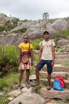Andringitra, Madagascar - November 16, 2022: Young man and woman standing on a rocky trail in a mountainous area. Young couple walking on a rocky trail in a mountainous area wearing flip-flops.