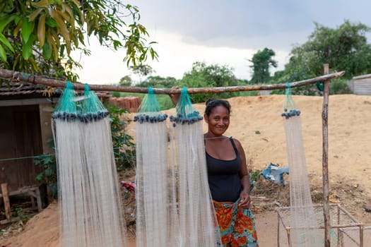 Miandrivazo, Madagascar - November 1st, 2022: A Malagasy woman selling fishing nets hung on a wooden stick.