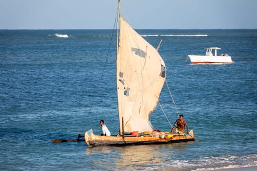 ANAKAO, MADAGASCAR - NOVEMBER 23, 2022: Fishermen using outrigger canoe carved from tree trunk to fish off the coast of Anakao. The primary source of livelihood in Anakao is fishing.