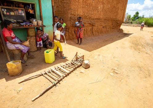 Vohitsoaka Ambalavao - November 6, 2022: Malagasy woman resting in front of market in shadow. In the foreground is a primitive wheelbarrow