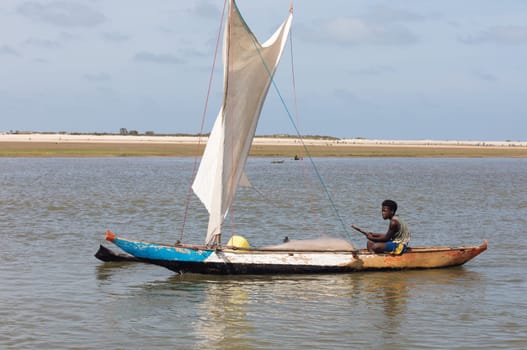 Morondava, Madagascar - November 3rd 2022: A fisherman sails back from the sea to the river on a sailboat in Morondava