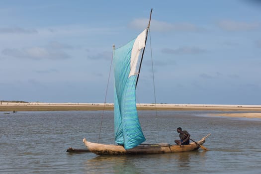 Morondava, Madagascar - November 3rd 2022: A fisherman sails back from the sea to the river on a sailboat in Morondava