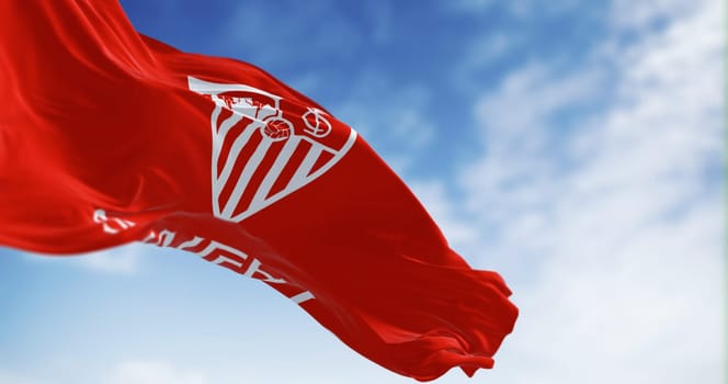 Seville, SP, May 2023: The flag of Sevilla Football Club waving in the wind on a clear day. Professional spanish football club. Illustrative editorial 3d illustration render.