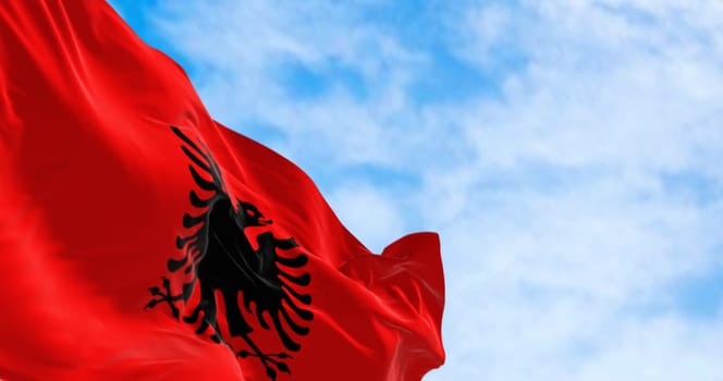 Albanian national flag waving in the wind on a clear day. Red flag with black two-headed eagle. 3d illustration render. Fluttering fabric.