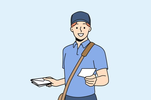 Guy works as postman and with smile holds out envelope with letter to screen, offering to use delivery correspondence. Man in postman clothes makes career in courier service or national postal company