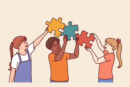 Diverse kids hold puzzle pieces as together solve problem together and demonstrate teamwork in learning process. Friendly multiethnic kids learn communication and collaboration to achieve goals