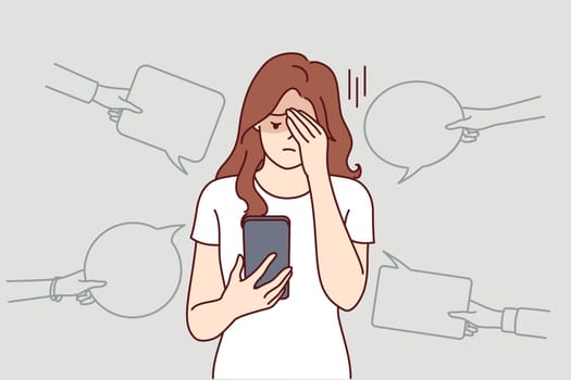 Upset woman with phone suffers from bullying and hate on social networks, receiving offensive messages and comments. Teenager girl is victim of internet bullying and discrimination from classmates