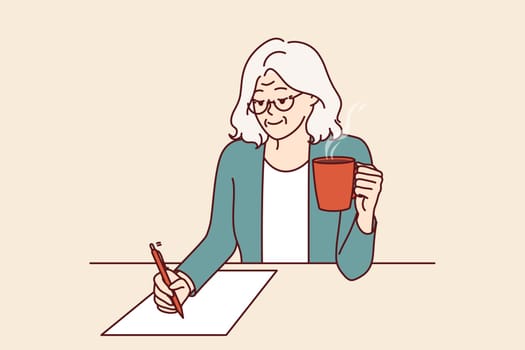 Elderly woman is writer, drinking coffee and sitting at table, inventing new book of bestseller and writing down text on paper. Grandmother with pen smiles and writes will or makes legal deal