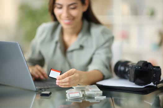Happy photographer downloading photos with card on laptop at home