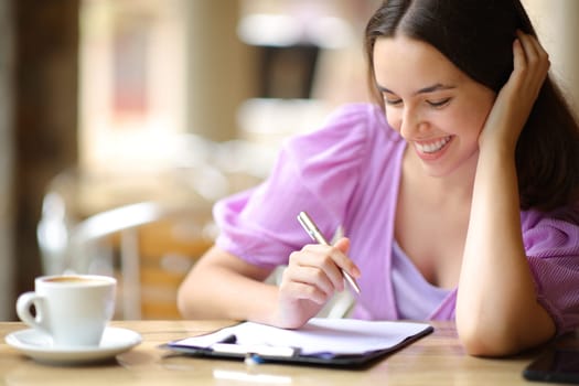 Happy woman reading and filling form in a restaurant terrace