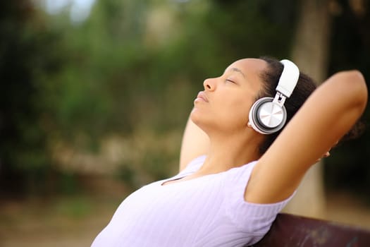 Side view portrait of a black woman resting listening audio with heaphone