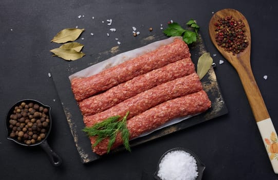 Raw lula kebab sausages on a board and spices, top view