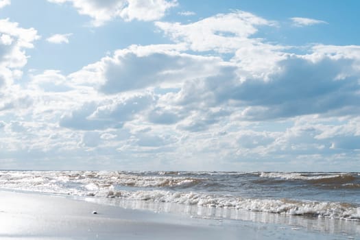 Wonderful view of clean beach seashore coastline, calm blue water, little sea waves, turquoise sky on sunny day. Summer, holiday, vacation, travelling, tourism, seascape, wallpaper, advertisement.