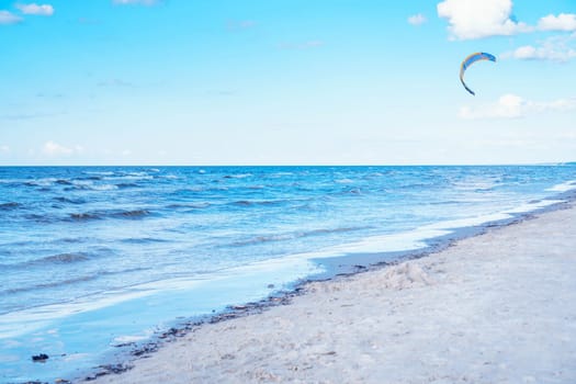 Wonderful view of clean beach seashore coastline, calm blue water, little sea waves, turquoise sky on sunny day. Summer, holiday, vacation, travelling, tourism, seascape, wallpaper, advertisement.