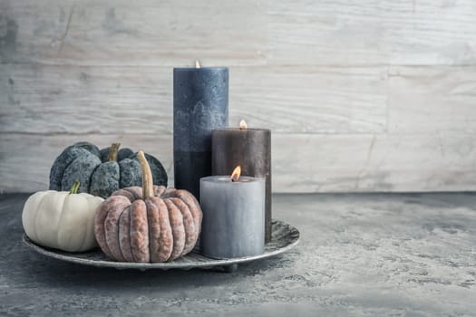 Autumn fall cozy mood composition for hygge home decor.  Candles and pumpkins for Thanksgiving in grey tone