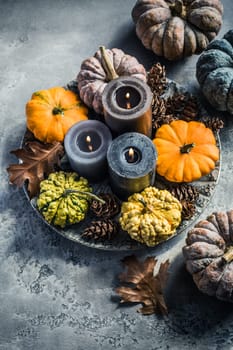 Autumn fall cozy mood composition for hygge home decor.  Candles and pumpkins for Thanksgiving in grey tone