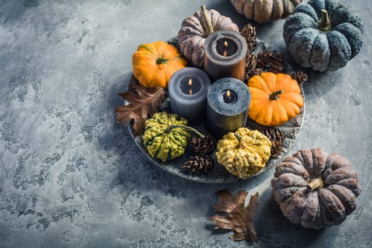 Autumn fall cozy mood composition for hygge home decor.  Candles and pumpkins for Thanksgiving in grey tone