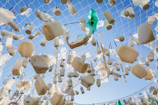 Plastic containers in fishing net against blue sky -  concept of garbage, water pollution, environmental issue