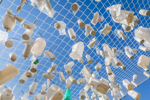 Plastic containers in fishing net against blue sky -  concept of garbage, water pollution, environmental issue