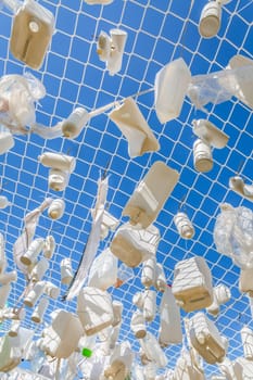 Plastic containers in fishing net against blue sky -  concept of garbage, water pollution, environmental issue