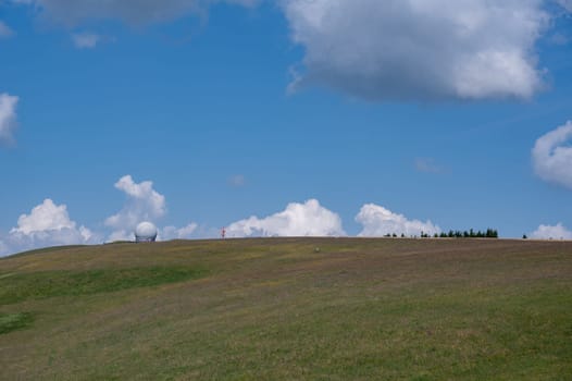 Radome (antenna dome) on the Wasserkuppe with a green meadow and blue sky and copy space